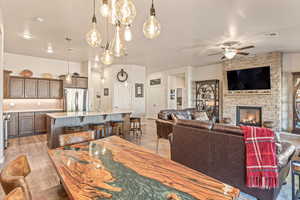 Dining space with a stone fireplace and ceiling fan
