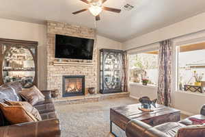 Living room featuring carpet floors, ceiling fan, and a fireplace