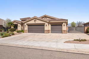 Mediterranean / spanish house with stone siding, stucco siding, concrete driveway, and an attached garage