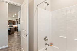 Full bath with shower / washtub combination and dark wood finished floors