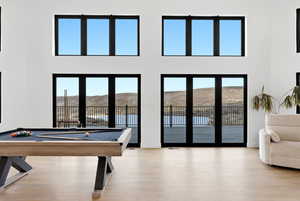 Game room with billiards, light wood-type flooring, a mountain view, and a high ceiling