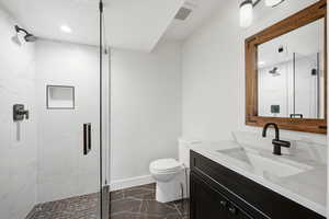 Bathroom with a marble finish shower, vanity, and dark marble finish floors