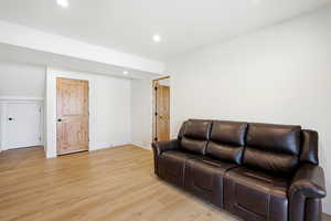 Living area with light wood-type flooring and recessed lighting