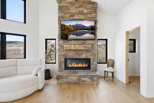 Living area with vaulted ceiling, a fireplace, and light wood finished floors