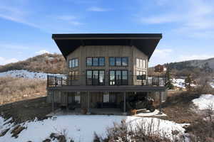Snow covered house with a mountain view and a patio area
