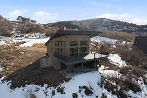 Snow covered rear of property with a patio area, a chimney, and a deck with mountain view