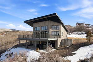 Snow covered house featuring a patio and a deck with mountain view