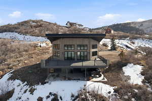 Snow covered house with a deck with mountain and lake views and a 1000 sq ft deck
