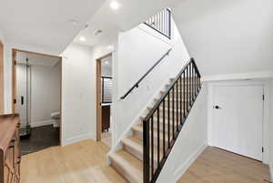 Stairs with wood finished floors and recessed lighting