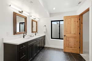 Full bathroom featuring double vanity, dark marble finish floors, and recessed lighting