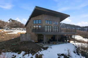 Snow covered rear of property with a patio area