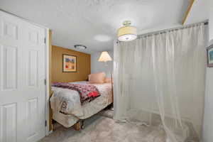 Bedroom with a textured ceiling and light colored carpet