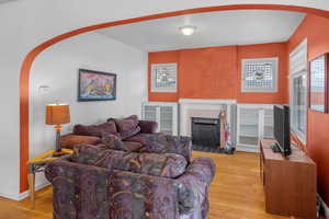 Living room with arched walkways, light wood finished floors, and a fireplace