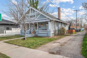 Bungalow with covered porch, a front yard, and a chimney