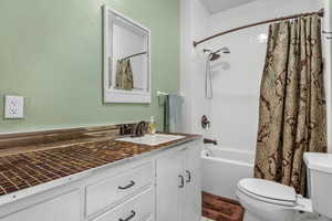 Full bathroom with vanity, shower / bath combination with curtain, and a textured wall