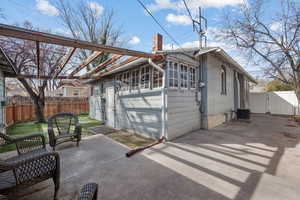 Back of house featuring a chimney, brick siding, a patio, and a gate
