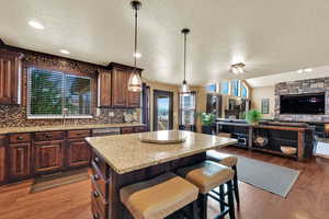 Kitchen featuring open floor plan, a breakfast bar, a center island, light stone countertops, and plenty of natural light