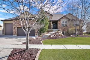 View of front of house featuring stone siding, concrete driveway, a front lawn, a shingled roof, and a garage