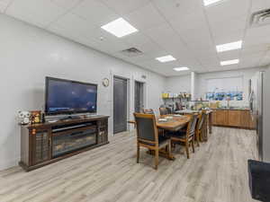 Dining room featuring light wood-style flooring and a drop ceiling