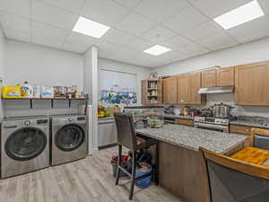 Laundry room featuring light wood-style flooring, washer and dryer, and a paneled ceiling