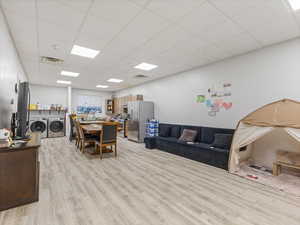 Living room featuring a paneled ceiling, light wood-style flooring, and washer and dryer