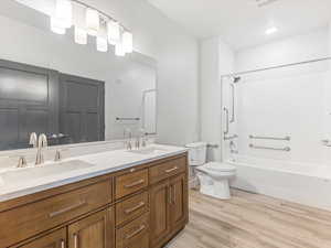 Bathroom featuring a dual vanity with a light wood-finish cabinet and stone countertop, undermount sinks, and brushed nickel fixtures