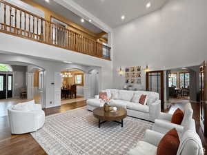 Great room with arched walkways, wood finished floors, suspended lighting, and a high ceiling