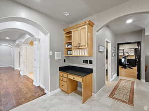 Hall featuring arched walkways, an office area, recessed lighting, and light wood-type flooring