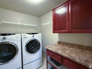 Basement Laundry room with a textured ceiling, washing machine and dryer, and cabinet space