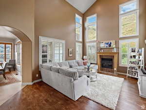 Family room with wood finished floors, arched walkways, a fireplace, healthy amount of natural light, and vaulted ceiling
