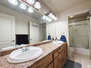 Second floor Bathroom with double vanity, light tile patterned floors, and combined bath / shower with glass door
