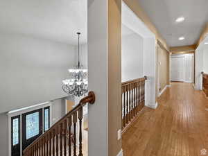 Hall featuring hanging lights, light wood-type flooring, and an upstairs landing