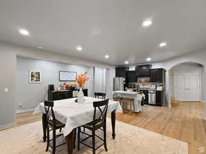 Basement Dining area featuring arched walkways, light wood-type flooring, and recessed lighting