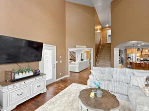 Family room featuring arched walkways, a high ceiling, dark wood finished floors, and recessed lighting