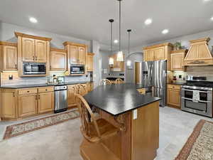 Kitchen with backsplash, a center island, stainless steel appliances, a breakfast bar area, and decorative light fixtures