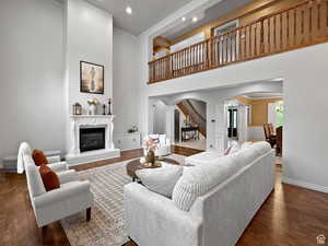 Great room with arched walkways, dark wood-style floors, a high ceiling, a premium fireplace, and recessed lighting