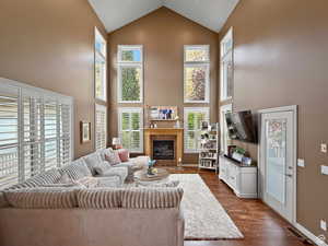 Family room featuring plenty of natural light, a fireplace, dark wood-type flooring, and a high ceiling