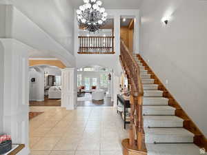 Foyer with arched walkways, a high ceiling, suspended lighting, light tile patterned floors, and decorative columns