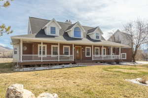 View of front of property featuring a porch, brick siding, a shingled roof, and a front yard