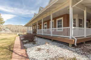 View of home's exterior with covered porch, brick siding, a mountain view, and a lawn
