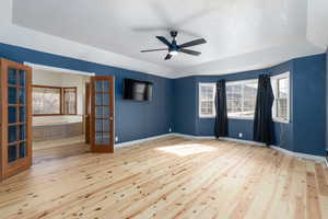 Empty room with light wood finished floors, ceiling fan, and french doors