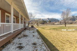 View of green lawn featuring covered porch and a mountain view