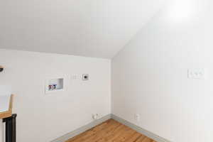 Laundry area with lofted ceiling, light wood finished floors, washer hookup, and electric dryer hookup