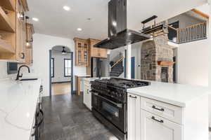 Kitchen with island range hood, high quality appliances, an island with sink, glass insert cabinets, and ceiling fan