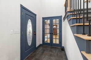 Foyer entrance with french doors, a high ceiling, and dark stone finish floors
