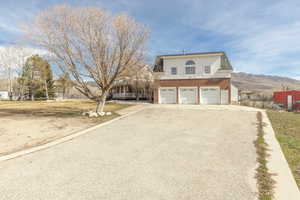 View of front facade with driveway, a garage, a front lawn, and a mountain view