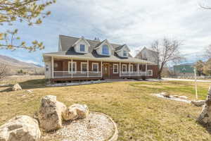 Farmhouse featuring covered porch, a front yard, a shingled roof, and brick siding