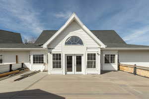Back of house featuring a deck, a shingled roof, and french doors
