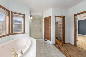 Full bathroom with a tub with jets, a shower stall, and a walk in closet
