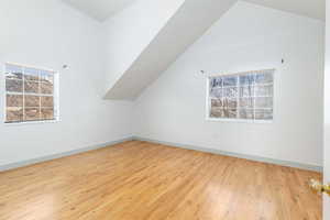 Additional living space featuring light wood-style flooring and vaulted ceiling